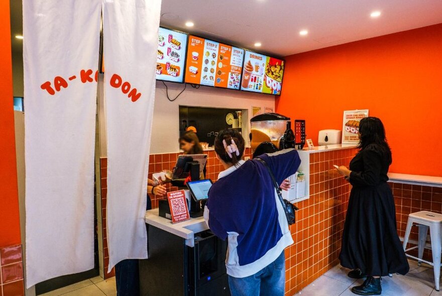 Two people lined up at a counter to order food