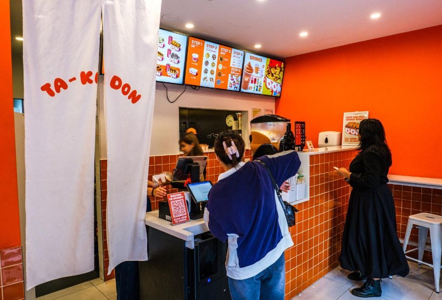 Two people lined up at a counter to order food