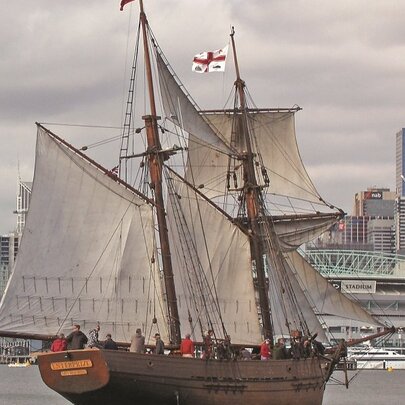 The 27-metre topsail schooner Enterprize a replica of a tall ship dating from 1830, sailing on water near Docklands, with Melbourne city buildings in the background.