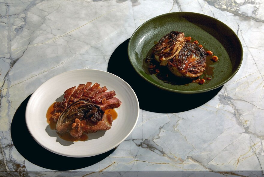 Two plates of food on a marble table.