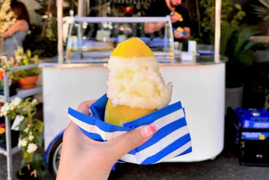 A scoop of gelato served in a hollowed out lemon with a blue serviette.