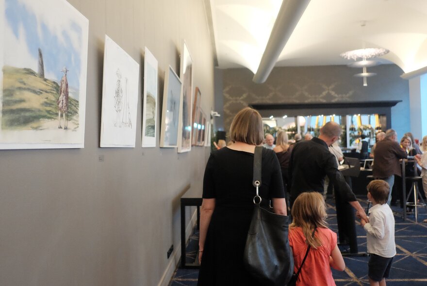 Adults with children in a foyer with art hung on the walls. 