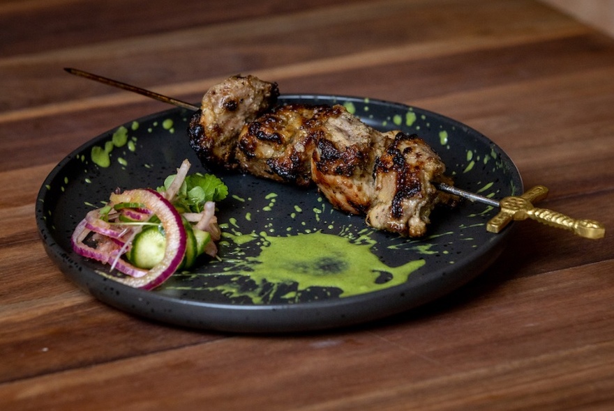 A kebab on a black plate on a table.