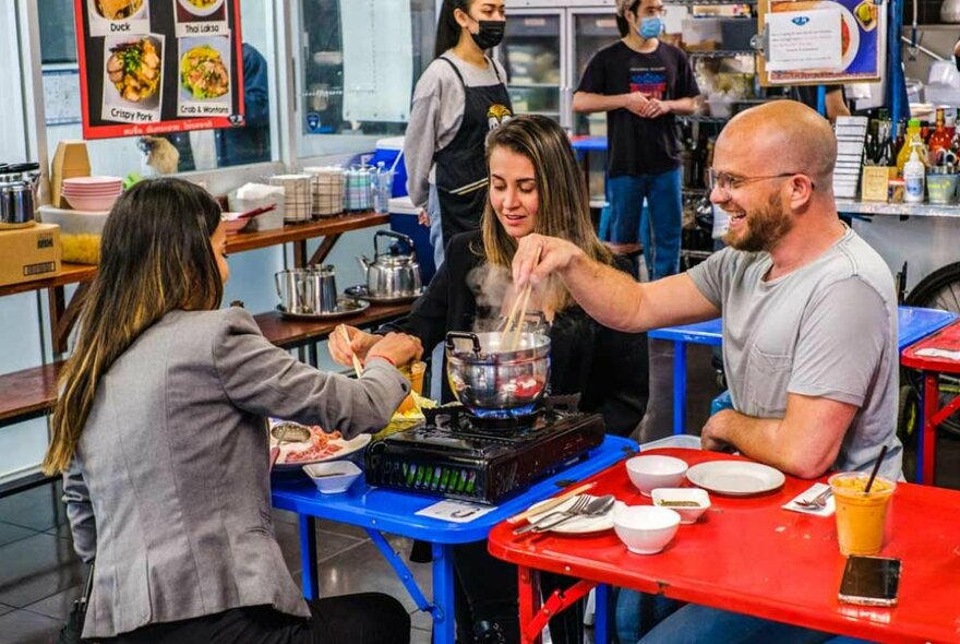 Three friends eating noodles at a restaurant