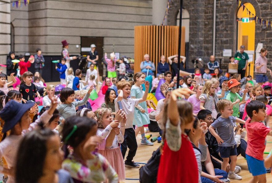 Kids enjoying a show at the State Library of Victoria, a bluestone wall behind them.