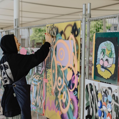 Person adding graffiti to an outdoor undercover walkway.