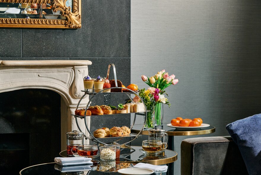 A small table at The Westin's Lobby Lounge set for a high tea with a tiered plate of savoury and sweet small bites, plus napkins and plates.