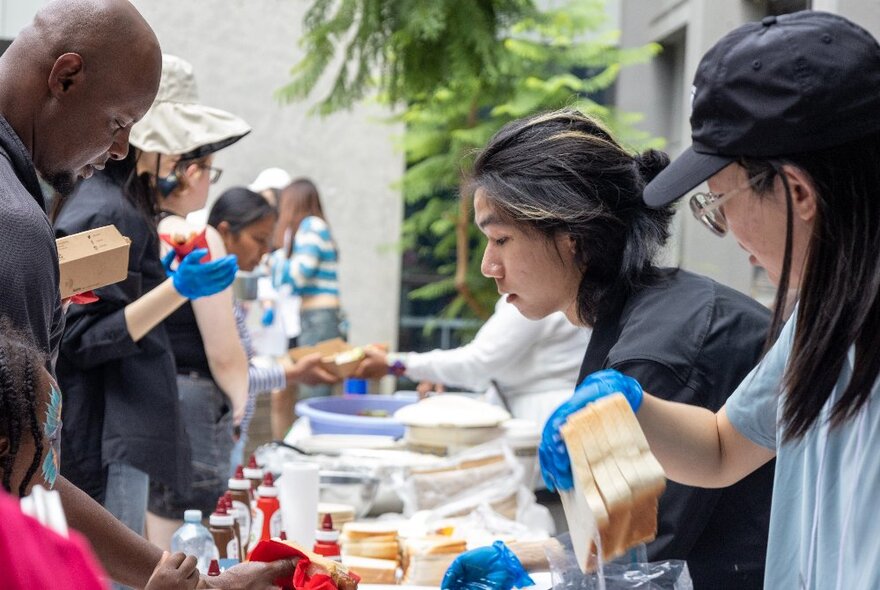 A long table with people serving food to those waiting. 