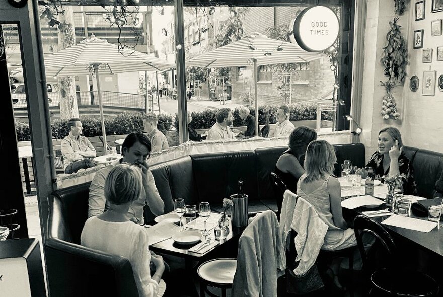 Interior of restaurant showing patrons seated at tables near a large window that overlooks the street.