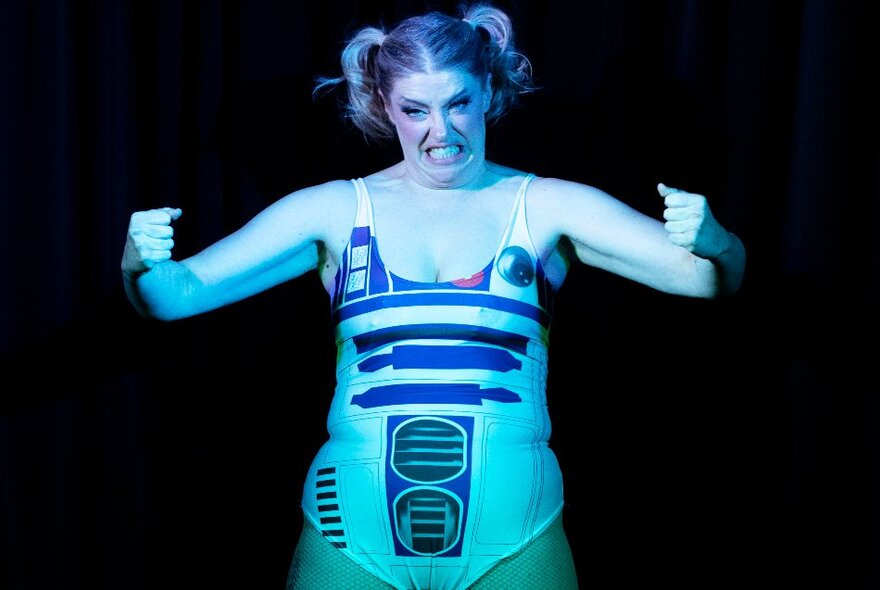 A woman in an R2D2 costume with pigtails, arms out and looking frustrated. 