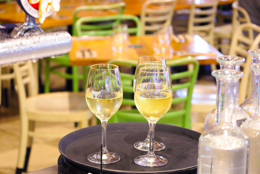 Three glasses of wine on a tray, on a table in a restaurant.