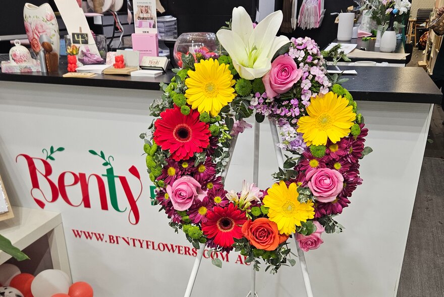 A wreath of colourful flowers in front of the service counter in a florist.