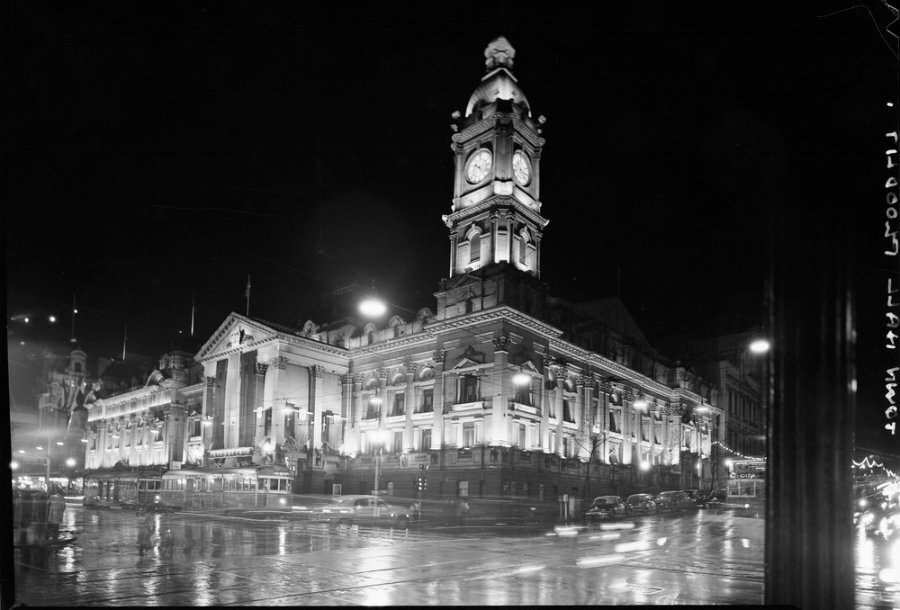 An old black and white photo of Melbourne Town Hall on a rainy night.