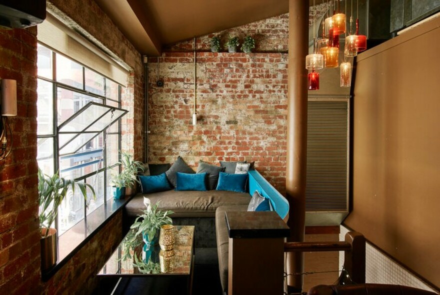 Large couch in a bar by an open window.
