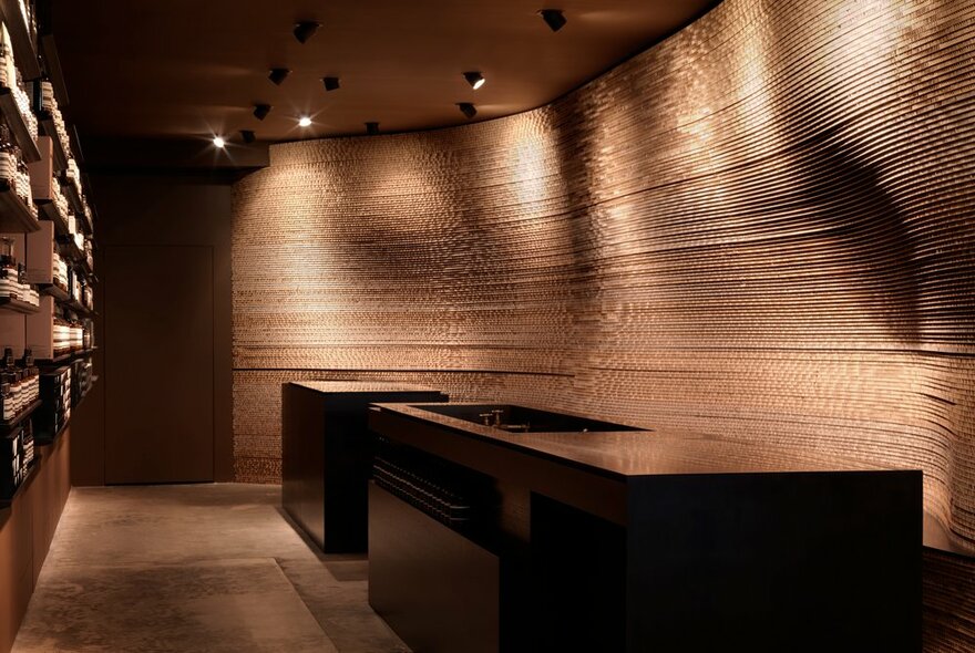 The interior of an Aesop shop with dark brown tones and dim lighting and a curved wall. 