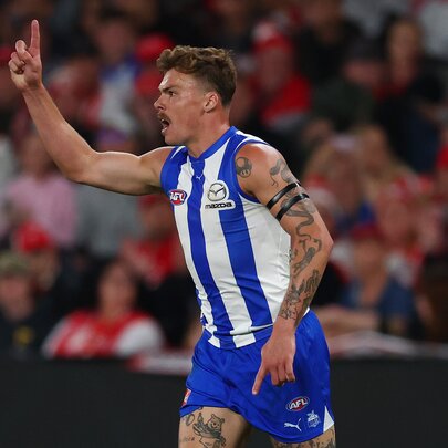 North Melbourne AFL football player with his arm raised in the air, and cheering, on the field during a match.