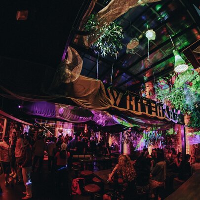 A crowd of people at night, seated and socialising at Whitehart Bar, a multi-level outdoor venue.