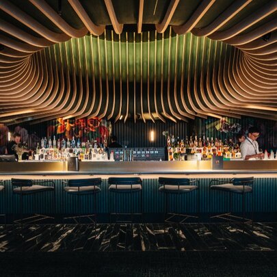 Dramatic sculptured ceiling of Amphora, with a bartender behind a dimly-lit bar with empty seats. 