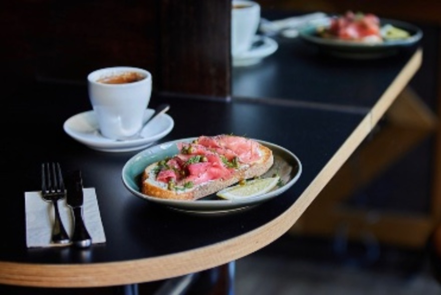 A black table set with bruschetta and coffee. 