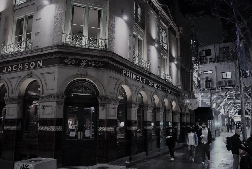 People walking past Young & Jackson's hotel at night.