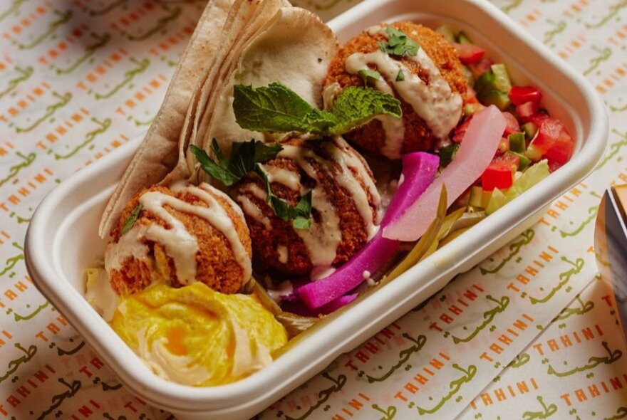 A Lebanese takeaway lunch box with falafel, pita bread and hummus.