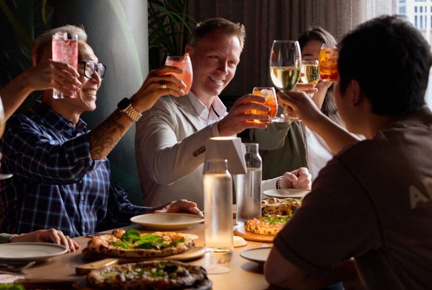 People at a dinner table raising their glasses in a toast. 