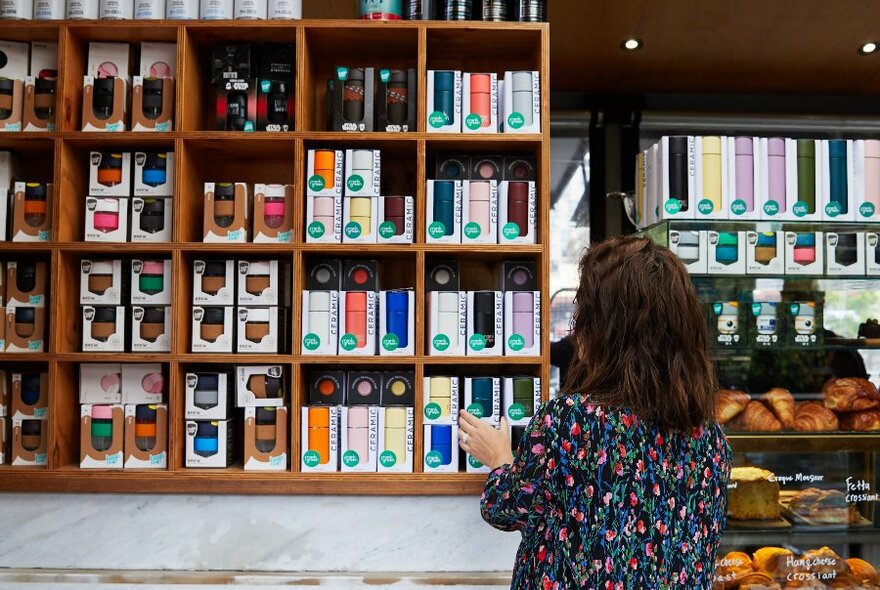 A woman standing in front of a display of reusable coffee cups and water bottles