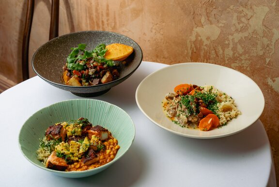 Three gourmet bowls with various fillings on a restaurant table.