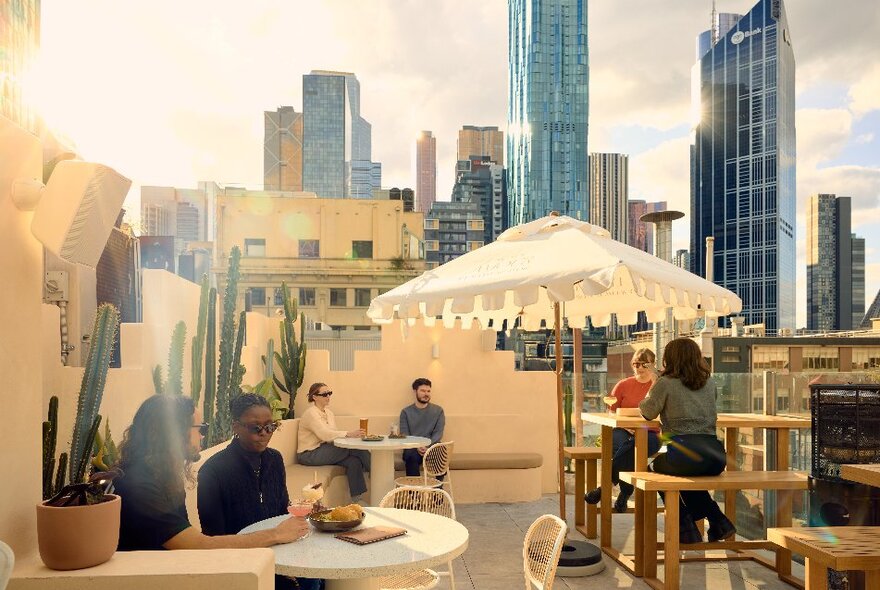 Six people seated at a Mexican-inspired rooftop bar on a sunny day in Melbourne.