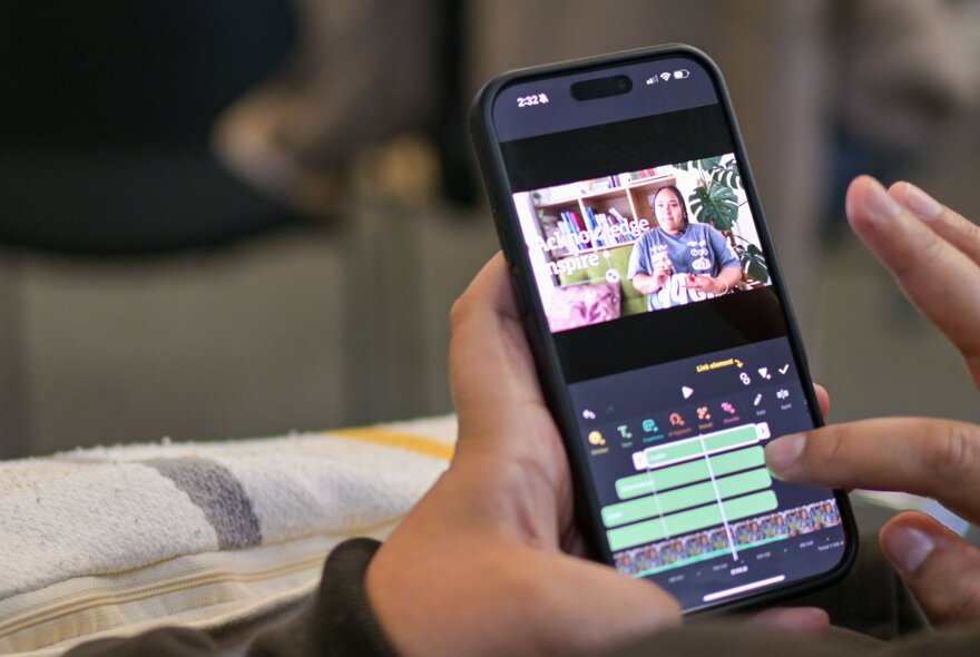 A person's hands editing a videon on a smartphone. 