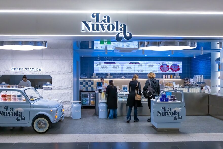 People being served a La Nuvola with a baby blue Fiat 500 in the left made into a crepe station. 