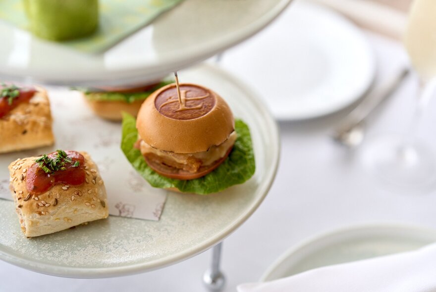 A traditional afternoon tea service featuring bite-sized sliders served on a tiered stand.