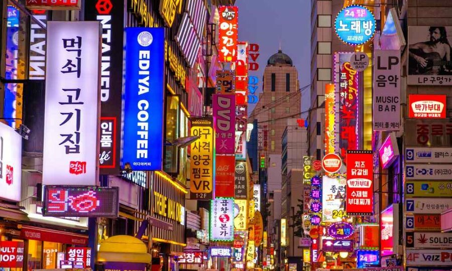 Lit up signs and advertising in a narrow street at night