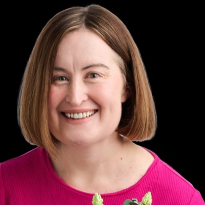 Comedian Katie Cullinan smiling against a pitch black background. 