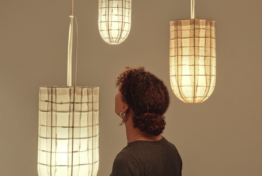 A person looking at illuminated paper sculpture lanterns.