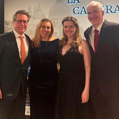 Four well-dressed people smiling for a group photo. 