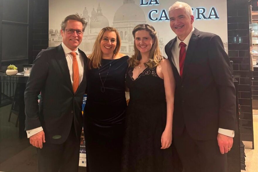 Four well-dressed people smiling for a group photo. 