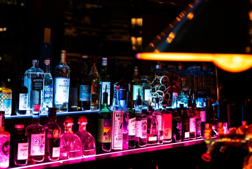 Two rows of bottles behind a bar.