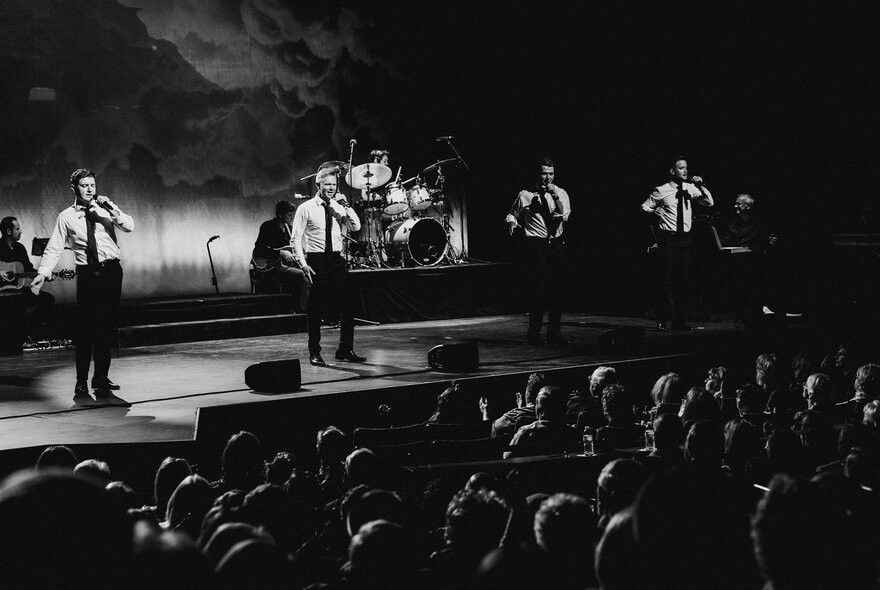 A black and white image of Celtic Thunder performing on stage before an audience