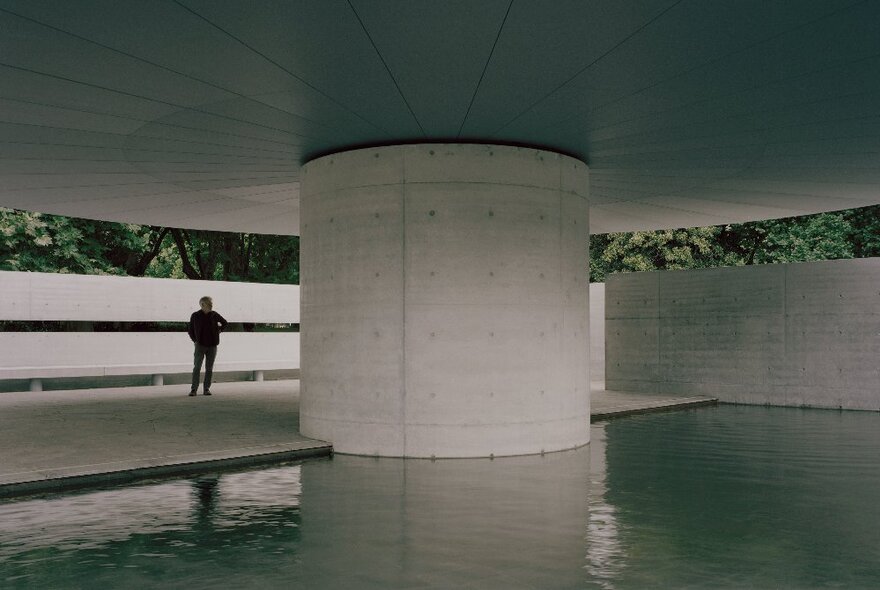 MPavilion building with a person standing next to a large column in water.