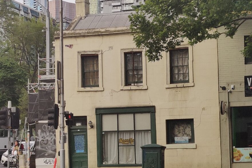 Old colonial two-storey building on a busy modern street corner.