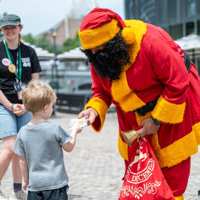 Koorie Klaus giving a present to a small boy in Fed Square. 