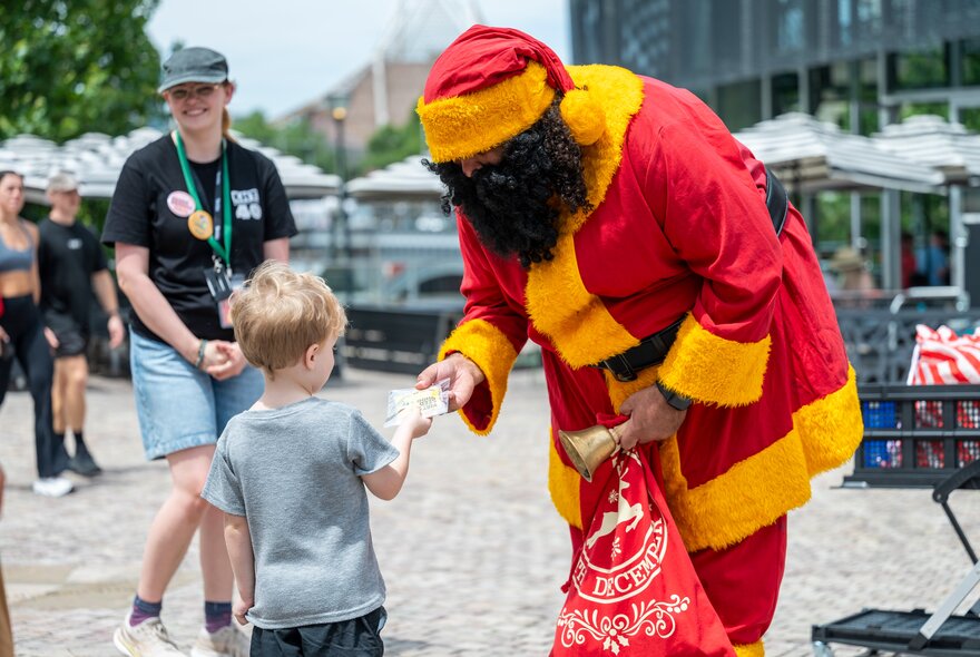 Koorie Klaus giving a present to a small boy in Fed Square. 