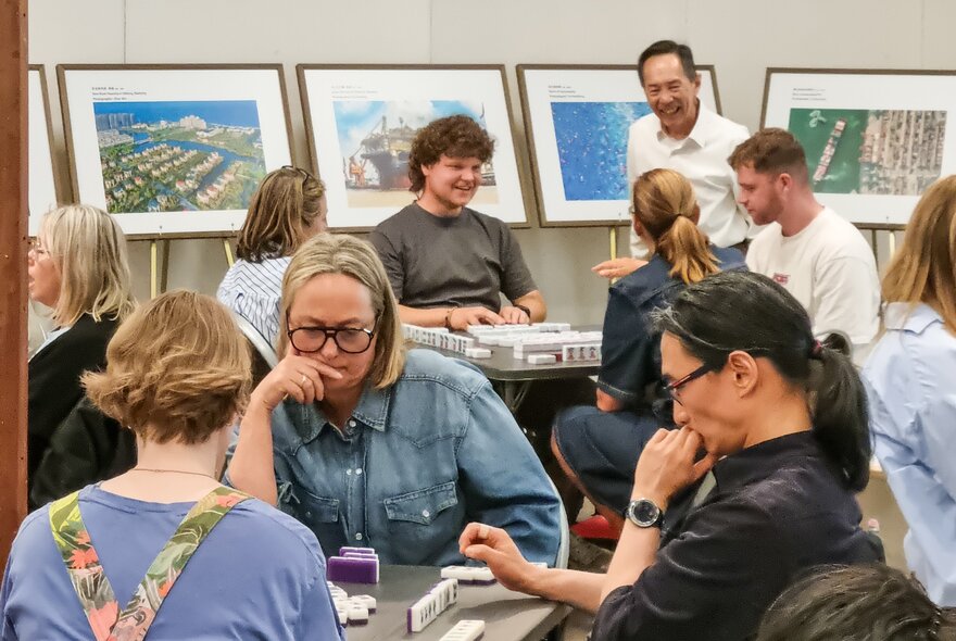 People seated around tables playing the game mahjong.