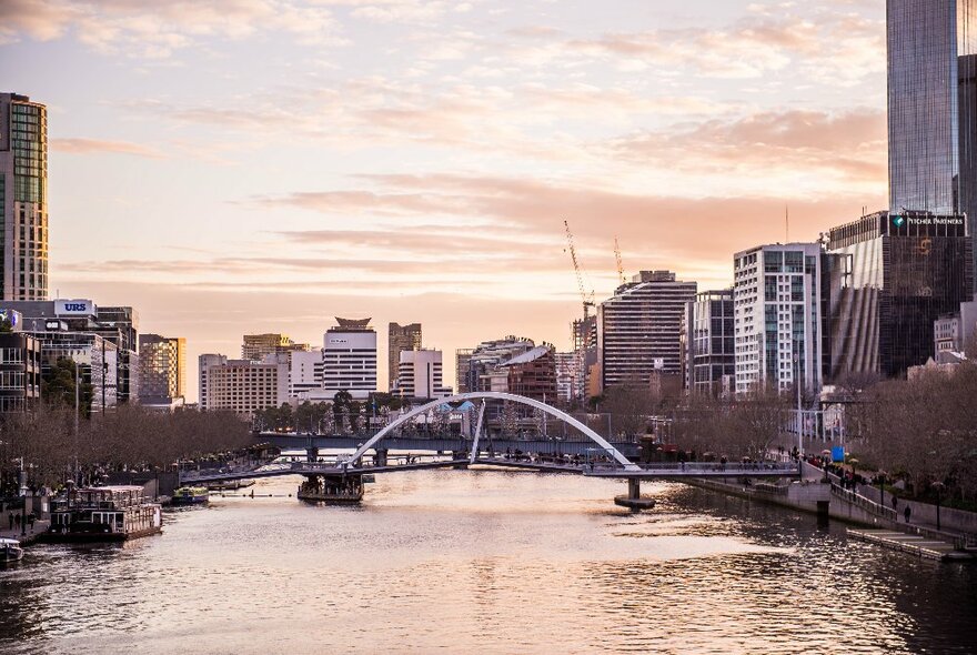 A sunset cruise ship going down the Yarra River with the Melbourne skyline in the background. 