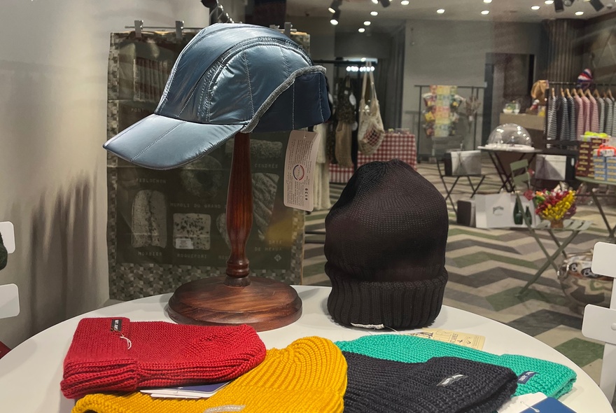 A small in-shop display featuring a stand with a cap and an array of different coloured beanies. 