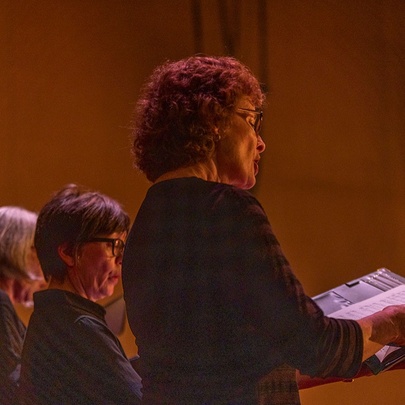 Back view of women singing in a choir with soft lighting. 
