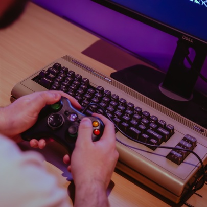A modern custom computer built inside a retro Commodore 64 case, being used with a modern Xbox game controller.