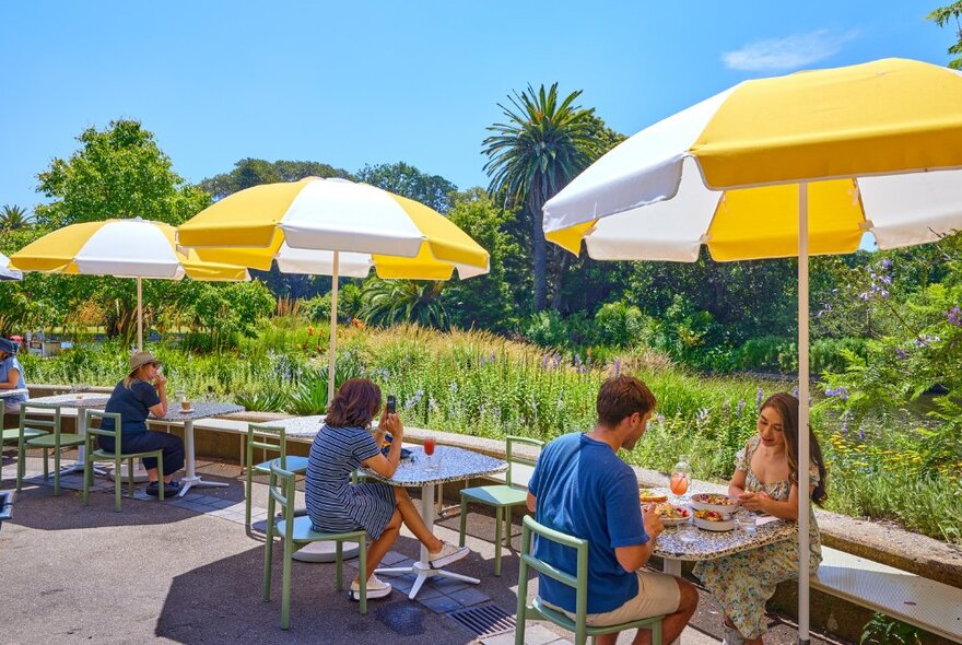 Outdoor dining area in botanic gardens with yellow and white umbrellas.