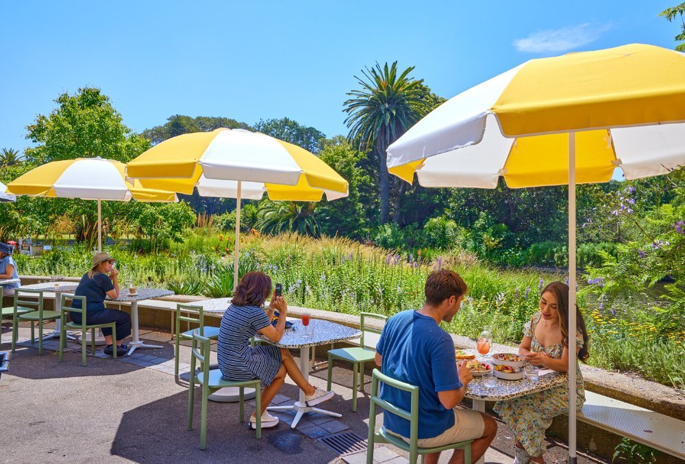 Outdoor dining area in botanic gardens with yellow and white umbrellas.
